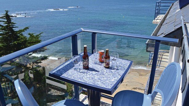 Ein Balkon mit Tisch für Zwei, der Blick auf Strand und Meer bietet.