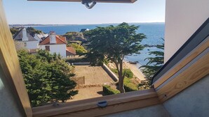 Blick aus einem Fenster auf einen Strand mit Häusern und einem klaren Himmel.