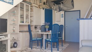 Ein Zimmer mit Schlafkoje, Schreibtisch und Essbereich mit blauen Stühlen.