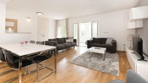 Een moderne woonkamer met een eethoek, twee banken, een televisie en een open haard.