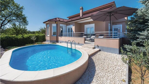 Een moderne villa met een zwembad, buitenmeubels en een overdekt terras.