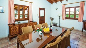 Un coin repas avec une table en bois, des chaises en osier et un vase rempli de fleurs.