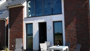 A modern house with a brick exterior, large windows, and a solar panel roof. - Apartment 10 - gate to the sea (Helgoland)
