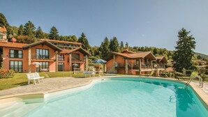 A resort with a swimming pool, multiple guest rooms, and a mountainous backdrop. - Beautiful apartment in Agra (VR) with outdoor swimming pool (Agra (VR))