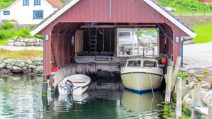 A red wooden boathouse with two boats docked inside.