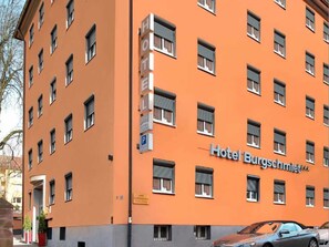 A multi-story hotel building with a prominent orange facade and the name "Hotel Burgschmiet" displayed on the front. - Double room - Hotel Burgschmiet GmbH (Nürnberg)
