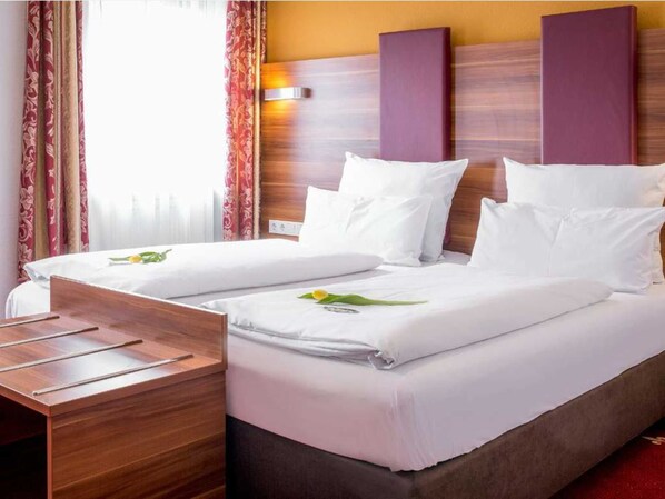 A hotel room with a bed, wooden headboard, and a desk.