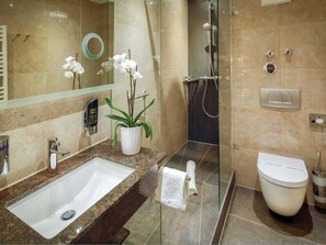 A modern bathroom with a granite countertop sink, a potted orchid, a glass shower enclosure, and a toilet with a lid. - Double room - Hotel Burgschmiet GmbH (Nürnberg)