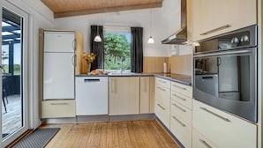 Una cocina moderna con horno empotrado, lavavajillas y un ventanal con cortinas.