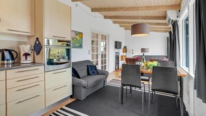 Una cocina moderna con horno integrado, un comedor con mesa y sillas, y una sala de estar acogedora con sofá.