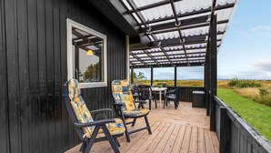 Una terraza de madera con mobiliario exterior, una pérgola y vistas al paisaje.
