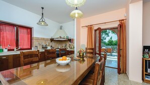Una cocina moderna con comedor, que incluye una gran mesa de madera, cortinas rojas y vistas al exterior.