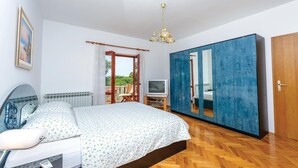 Un dormitorio con cama, televisor, armario y un espejo grande.