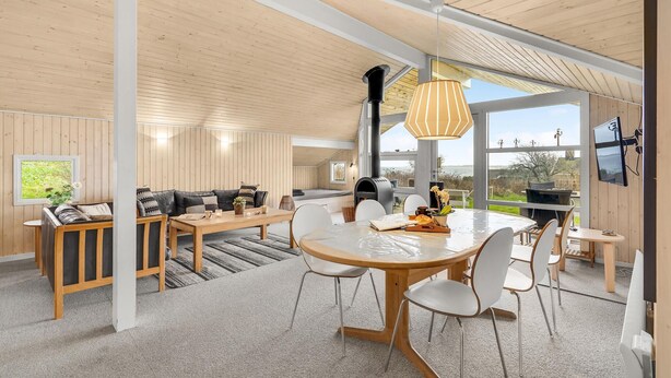 Un intérieur moderne avec un plafond en bois, une table à manger centrale et un ensemble de canapés.