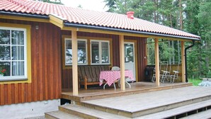Eine Holzjagdhuette mit Veranda, einem Tisch mit kariertem Tischlein und einer Bank.