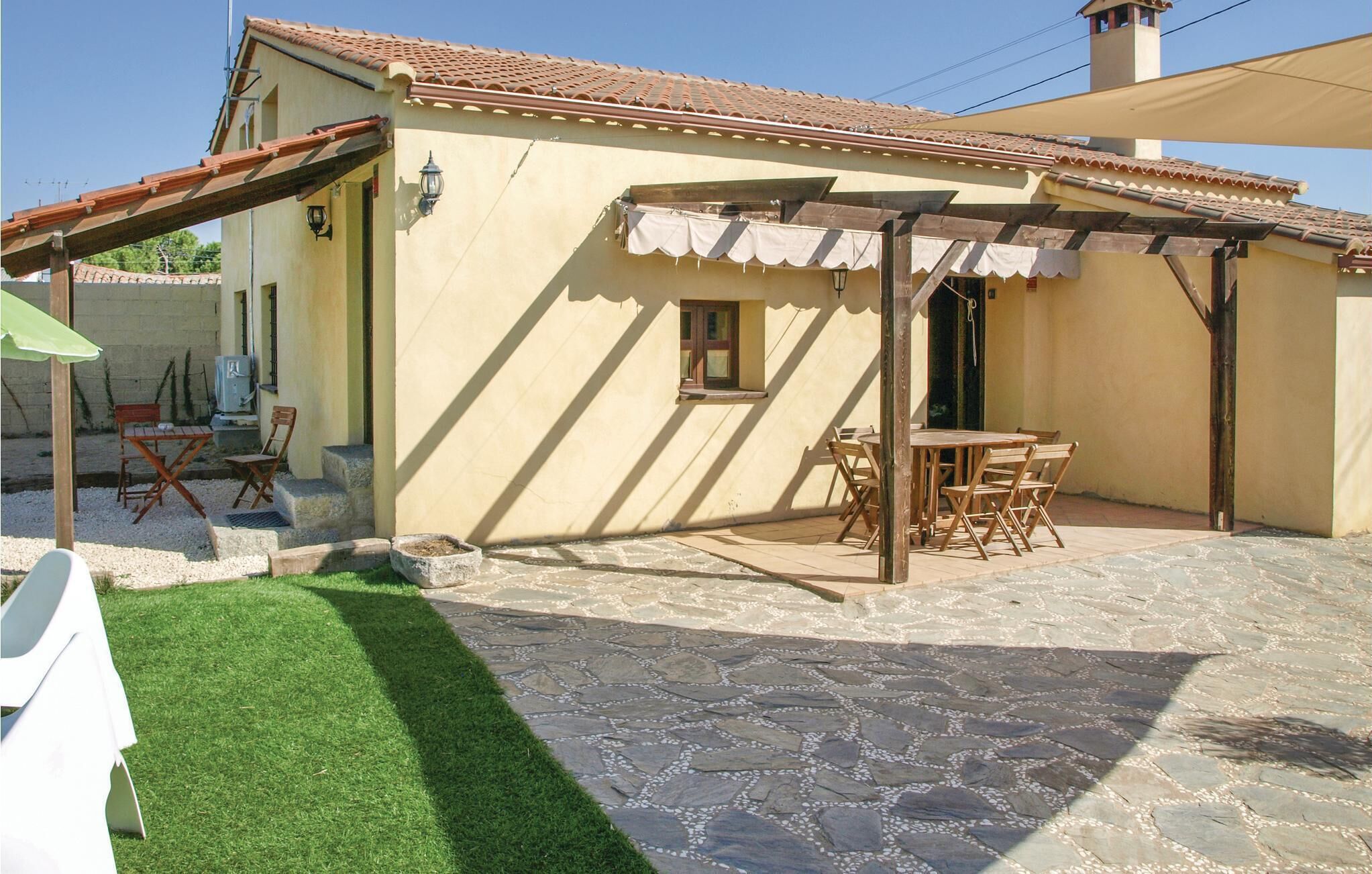 A patio area with a stone floor, a covered seating area with chairs, and a small table.