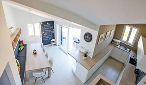 A modern kitchen with a built-in oven, a sink, and a dining area with a table and chairs. - Holiday apartment with 2 terraces (Vantačići)