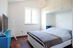 A bedroom with a bed, a TV on a dresser, a window, and a wardrobe. - Holiday apartment with 2 terraces (Vantačići)