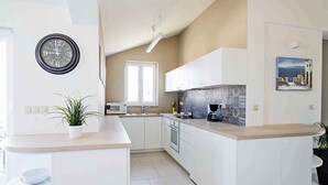 Une cuisine moderne avec des meubles blancs, un îlot central, un four à micro-ondes et une machine à café.