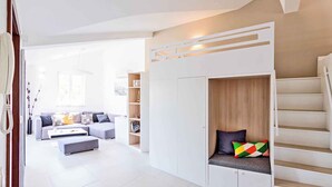 Un salon moderne avec un canapé, une table basse et un coin salon intégré doté d’un escalier.