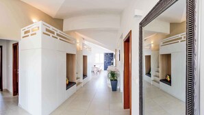 Un hall d’entrée spacieux avec des lits superposés, un grand miroir et une plante en pot.
