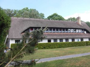 A building with a thatched roof, white walls, and a long row of windows.
