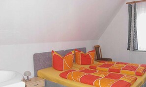 A bedroom with a bed, a nightstand, a lamp, and a window with curtains. - Apartment Bodenkieker (Dreschvitz)