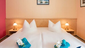 A hotel room with two beds, white linens, matching pillows, bedside lamps, and a painting on the wall. - Villa Cosima - VC 13 (Heringsdorf)