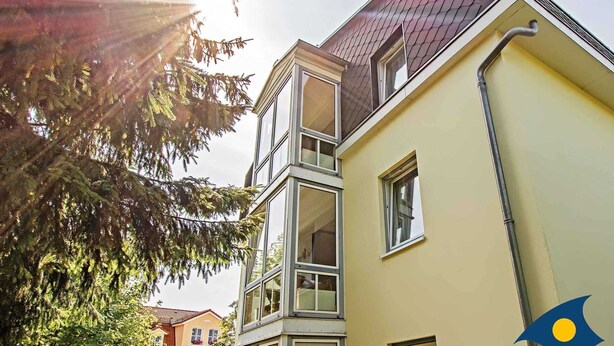 A multi-story building with a yellow facade and a red roof, featuring large windows and a visible chimney. - Villa Cosima - VC 13 (Heringsdorf)