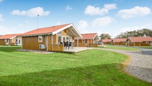 Eine Reihe von Holzhäuschen mit roten Dächern, jedes mit einer Veranda und einer Sitzgelegenheit im Freien.