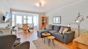 A modern living room with a grey sofa, a small round table, and a bookshelf. - Bergen: stylish apartment with parking space and beach chair - FeWo Bergen (Binz)