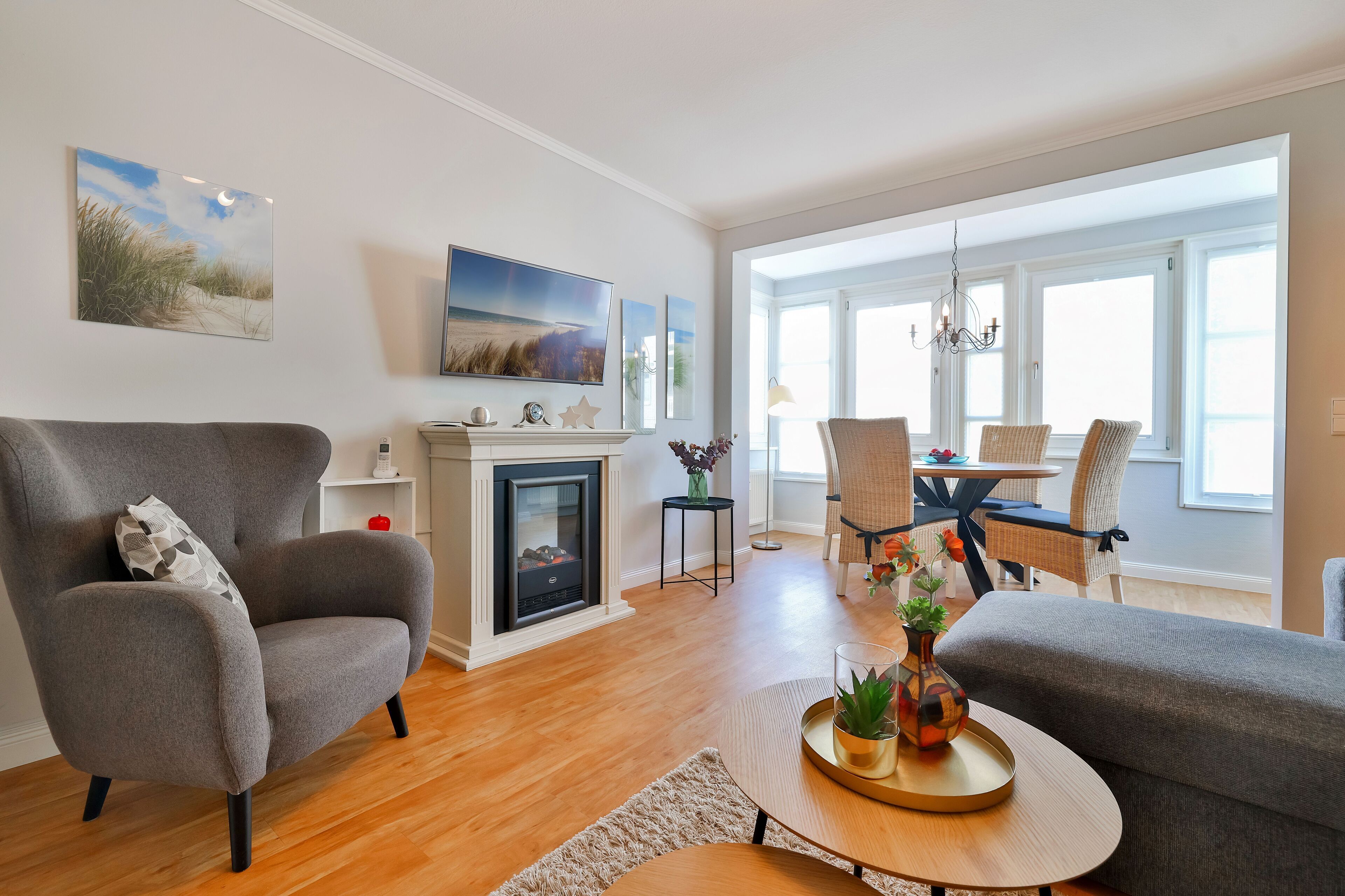 Una sala de estar moderna con chimenea, asientos cómodos y un comedor con luz natural.