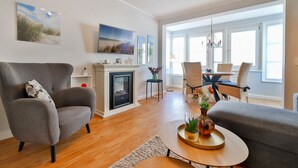 A modern living room with a fireplace, comfortable seating, and a dining area with natural light. - Bergen: stylish apartment with parking space and beach chair - FeWo Bergen (Binz)
