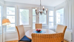A dining area with wicker chairs, a round table, and a chandelier. - Bergen: stylish apartment with parking space and beach chair - FeWo Bergen (Binz)