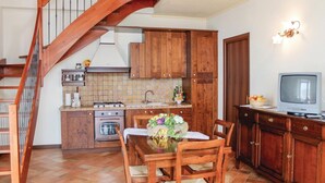 Une cuisine avec des meubles de rangement en bois, une cuisinière et une table à manger avec des chaises.