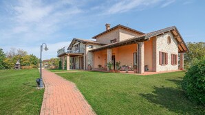 Une maison à deux étages avec une façade en briques, un balcon et une allée pavée.
