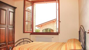 Une chambre à coucher avec un lit, une armoire en bois et une fenêtre donnant sur un immeuble en briques.