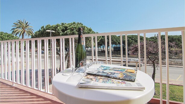 A balcony with a white table displaying magazines and a bottle.