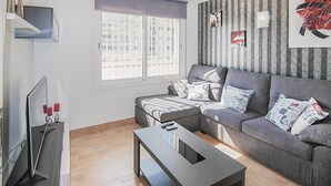 A modern living room with a grey sofa, a coffee table, and a TV on a stand.