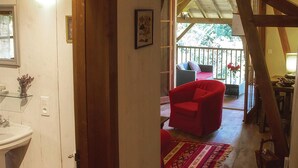 A wooden interior with a red chair, a glass table, and a view of an outdoor balcony with a red sofa. - Awesome home in Masseube with sauna (Masseube)