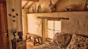 A rustic bedroom with a wooden bed, a bench, a small table, and a window with a view of the outside. - Awesome home in Masseube with sauna (Masseube)