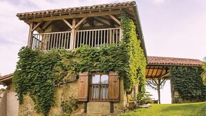A two-story stone house with a wooden balcony and ivy-covered walls. - Awesome home in Masseube with sauna (Masseube)