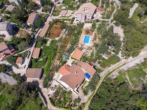 An aerial view of a residential area with houses, a swimming pool, and surrounding greenery. - Holiday apartment with balcony (Veli Lošinj)