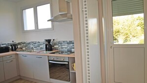 Eine Küche mit gefliestem Spritzschutz, einer Kaffeemaschine und einem Fenster über der Spüle.