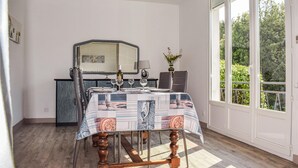 Ein Essbereich mit einem Tisch für zwei Personen, einem Spiegel darüber und Blick auf Grünanlagen durch große Fenster.