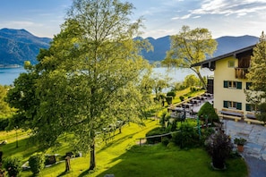 A mountain lodge with a dining area, outdoor seating, and a view of the lake and mountains.