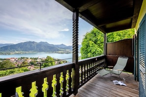 A wooden balcony with a view of a lake and mountains.
