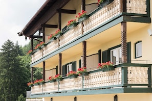 A multi-story building with balconies adorned with red flowers, wooden beams, and a traditional architectural style.