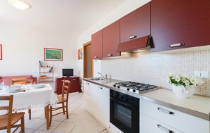 Compact kitchen area with gas stove, oven, and dining table.