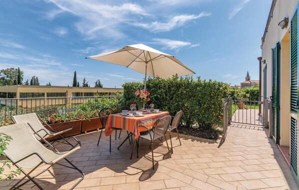 An outdoor patio with a table set for dining, surrounded by chairs and an umbrella. - Pet friendly apartment (S.Bartolomeo Mare IM)